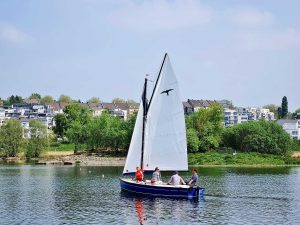 Vier Menschen segeln mit der Kreuzknoten vor der Insel im Phoenix See