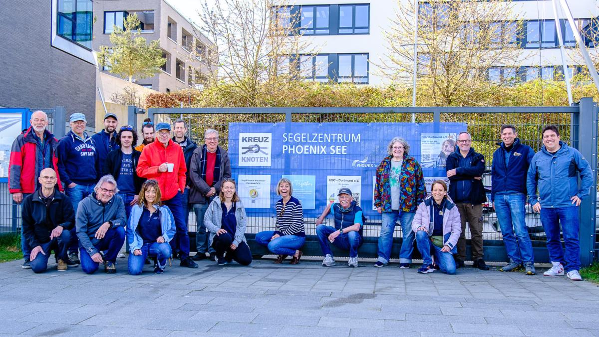Menschen aus den Vereinen am Tor zu den Landliegeplätzen vor dem neuen Banner der Vereine.